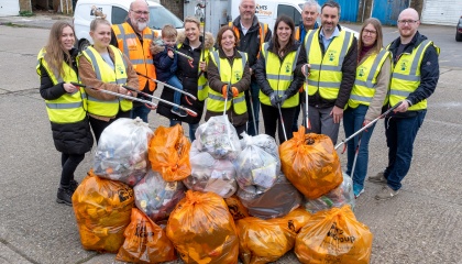 A group of Harlow spring cleaners in high visibility vests, holding their litter pickers and standing in front of 14 bags of rubbish collected. 