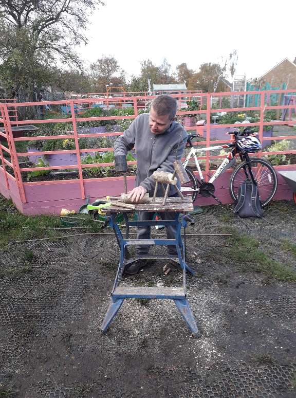 A man cutting wood with Plant Pots and Wellies