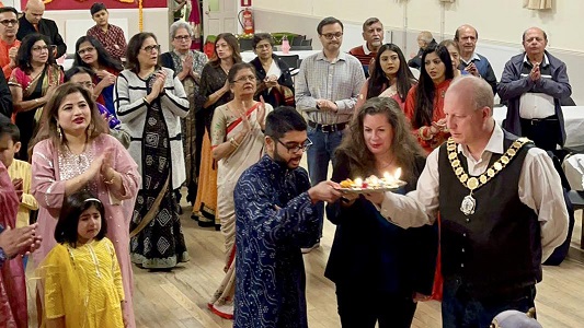 Group of people lighting candles in a community hall for Diwali