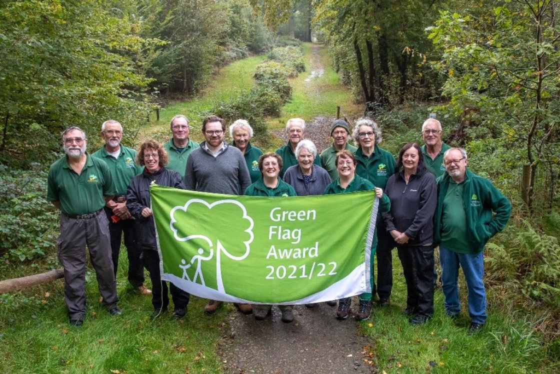 Parndon Wood Nature Reserve Green Flag Award Image of volunteers and council staff at Parndon Wood Nature Reserve holding a flag with the wording: Green Flag Award 2021/22