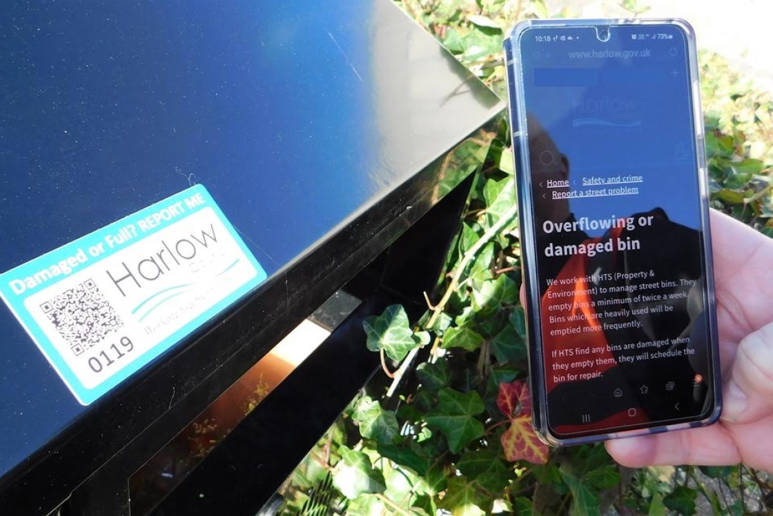 Image of QR code sticker on a litter bin with a mobile phone