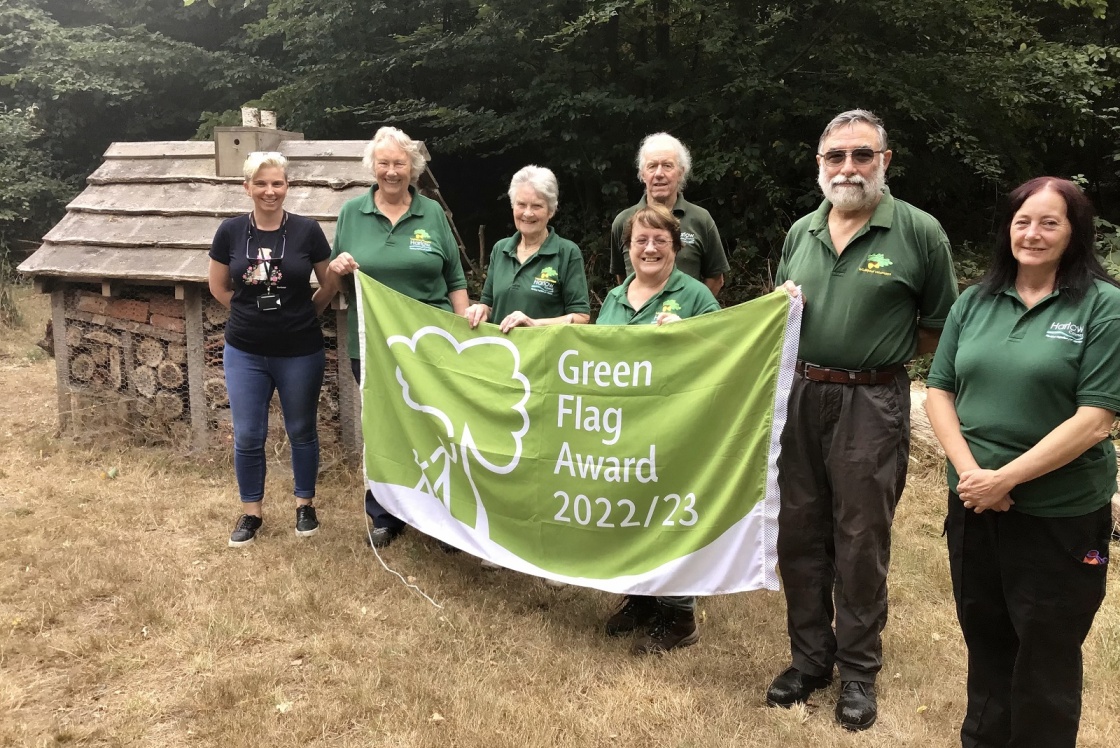 Group of Parndon Wood staff holding green flag next to bee hotel