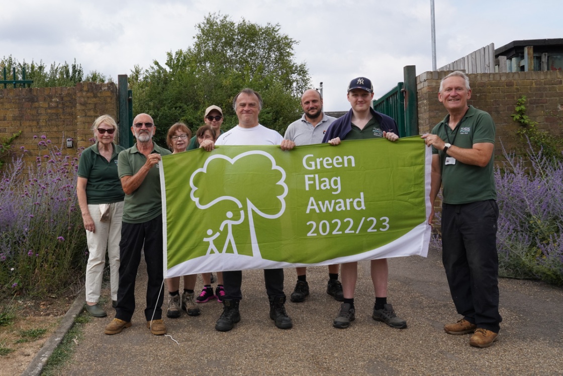 Group of Town Park staff holding green flag in front of Walled Garden
