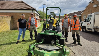 Councillor Nicky Purse with one of the HTS grass cutting crews at Fountain Farm. They are standing next to a large ride on mower