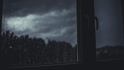Image of rain on windows with storm clouds gathering in the sky 