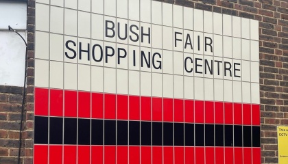 Image of Bush Fair shopping Centre sign on white tiles with red and black tiles underneath