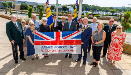 Image of council personnel and armed forces representatives with the Armed Forces Day Flag 