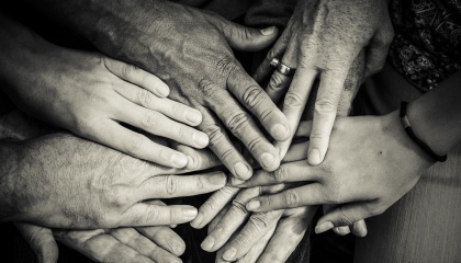 Black and white image of 7 different hands touching 