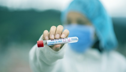 Person in ppe holding a covid-19 test tube